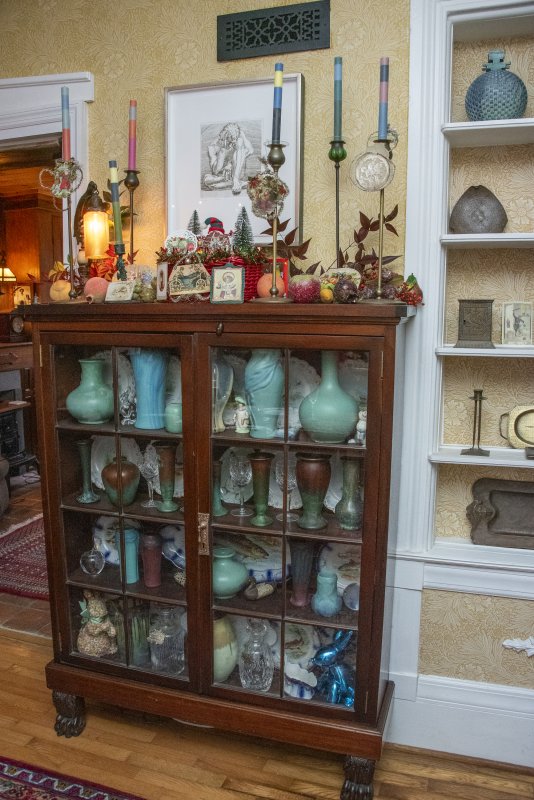 Antique vases stored in a vintage cabinet topped with seasonal ephemera set the scene for the Victorian home of Jared Christopher and Merle McCann.